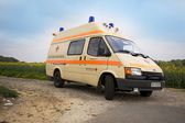 Foto: Krankenwagen von hinten vor einem Rapsfeld.