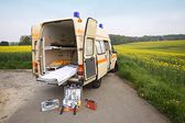 Foto: Krankenwagen von vorn vor einem Rapsfeld.